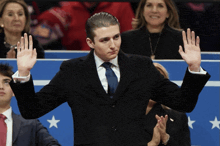a man in a suit and tie is raising his hands