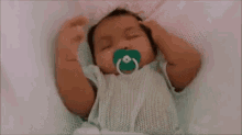 a baby is sleeping in a crib with a pacifier in its mouth .