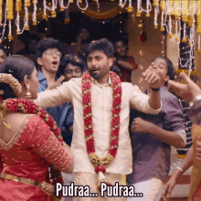 a bride and groom are dancing in front of a crowd and the bride is wearing a garland of flowers