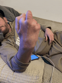 a man laying on a couch giving the middle finger while wearing a nike hoodie