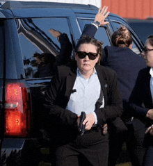 a woman in a suit and sunglasses holding a gun