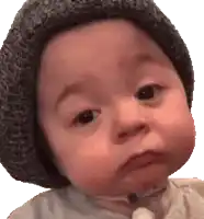 a baby wearing a knitted hat is making a funny face