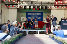 a group of people sitting on a stage with a banner that says demokratie beginnt bei sexualitat