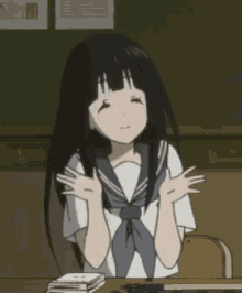 a girl with black hair is sitting at a desk with her arms outstretched