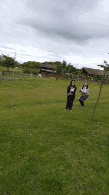 three women standing in a grassy field with a house in the background