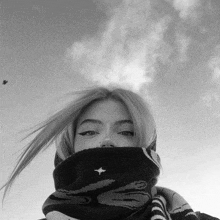 a black and white photo of a woman wearing a scarf covering her face