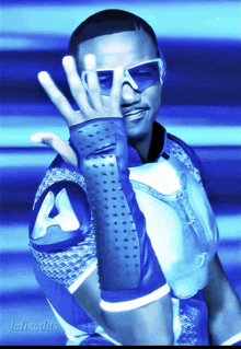 a man wearing sunglasses and a blue shirt with the letter a on the sleeve