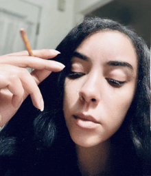 a girl with a nose ring is holding a cigarette in her hand
