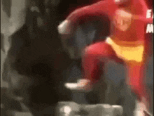 a man in a red superhero costume is jumping in the air in a blurry photo .