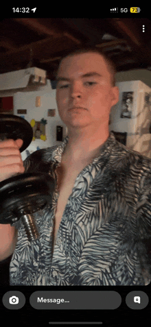 a man in a shirt is holding a dumbbell in front of a phone that says 14:32