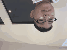 a man wearing glasses is upside down on a ceiling