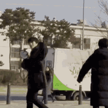 a man is holding a megaphone in front of a green and white truck that says ' korean ' on it