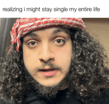 a man with curly hair and a beard is wearing a red and white scarf around his head