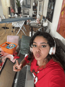 a woman wearing headphones is sitting in front of a laptop and making a funny face