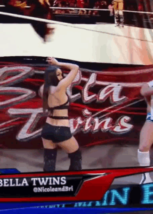 a woman is dancing in front of a banner that says bella twins on it