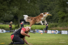 a dog is jumping in the air to catch a frisbee while a woman looks on