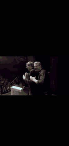 two men standing at a podium in front of a crowd of people