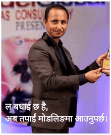 a man in a suit is holding a trophy in front of a sign that says as consult present