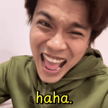 a man wearing a green jacket is making a funny face and the word haha is on his face
