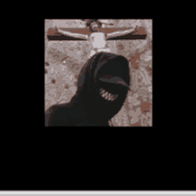 a man in a black hoodie is smiling in front of a crucifix