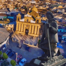 an aerial view of a city with a statue of a man holding a stick in front of a church