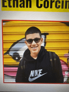 a boy wearing sunglasses and a black nike hoodie