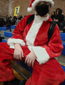 a man dressed as santa claus sits on a bleacher