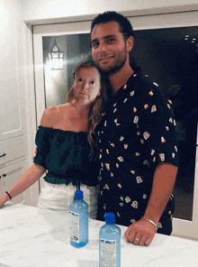 a man and a woman are posing for a picture with two bottles of soft water