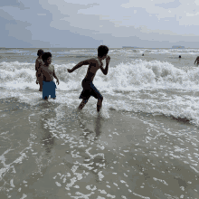 a shirtless boy in blue shorts is running into the ocean