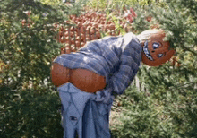 a scarecrow with a pumpkin on his head is standing in front of pumpkins