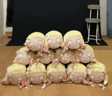 a bunch of stuffed dolls are stacked on top of each other on a wooden floor