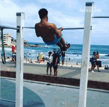 a man is doing a pull up on a bar in front of the ocean with the words people are awesome above him