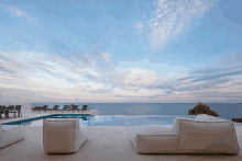 a swimming pool with a view of the ocean and chairs