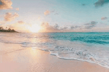 a beach with a sunset in the background and waves crashing on the shore .