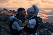 a man and a woman standing next to each other on a rocky hillside