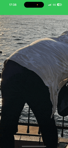 a phone screen shows a person standing in front of a body of water and the time is 17:38