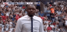 a man in a white shirt and tie is standing in front of a crowd of people in a stadium .