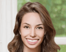 a woman with brown hair is smiling and looking at the camera