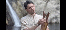 a man is holding a harp in front of a waterfall and says `` i 'm only kjv '' .