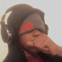 a person wearing headphones covering their face with a hat that has the number 5 on it