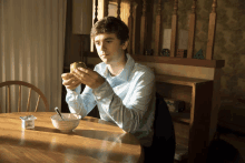 a man sits at a table with a bowl of cereal and a container of yogurt