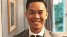 a man in a suit and tie is smiling for the camera in a room .