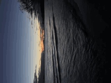 a sunset over a body of water with a few trees in the background