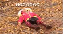 a baby is laying on the ground in a pile of leaves and looking at the camera .