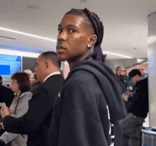 a man in a black hoodie stands in a crowd