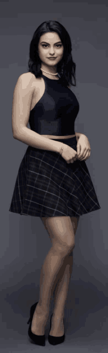 a woman in a blue halter top and plaid skirt