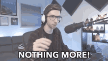 a man wearing headphones and glasses is sitting in front of a microphone with the words nothing more below him