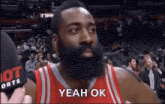 a basketball player with a beard is being interviewed by a reporter while wearing a red jersey .