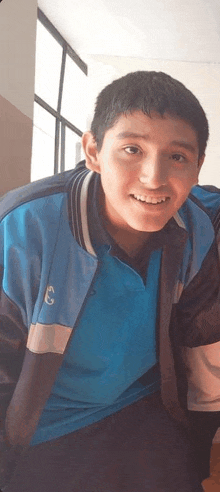 a young man wearing a blue shirt with the letter c on it smiles for the camera