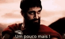 a man with a beard is wearing a red cape and saying um pouco mais ! .